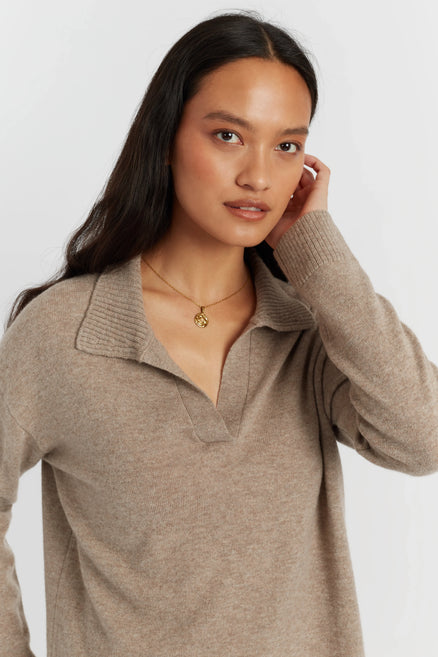 Woman wearing a beige sweater against a white background