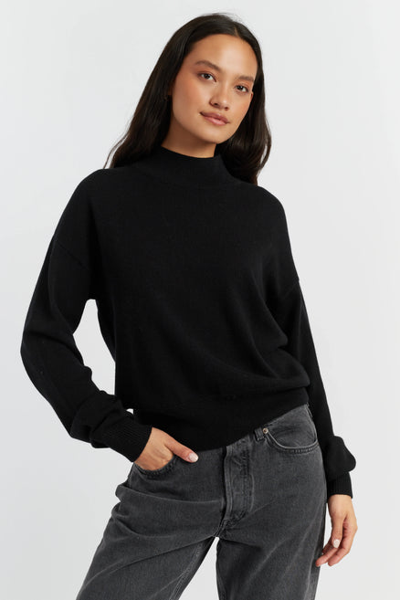 Woman wearing a black sweater and gray pants on a white background