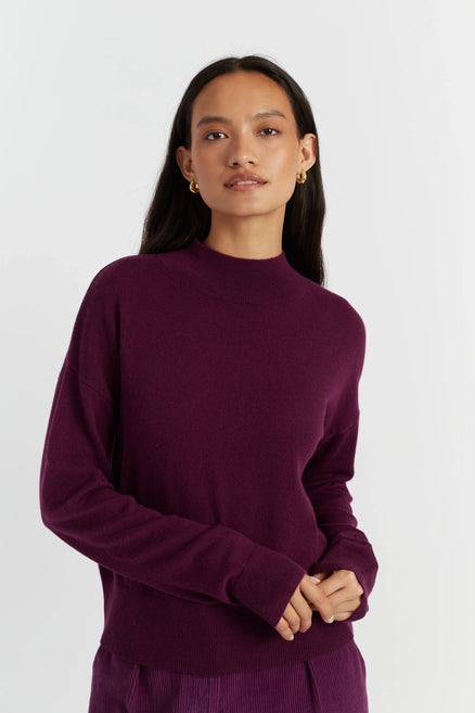 Woman wearing a purple sweater against a white background