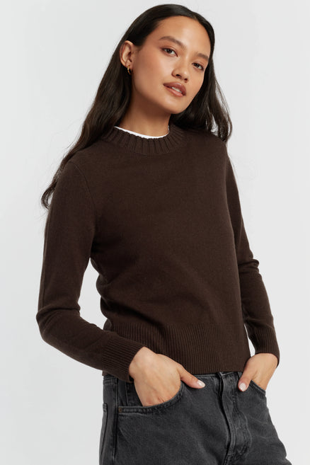 Woman wearing a brown sweater against a white background