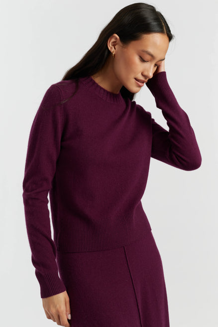 Woman wearing a purple sweater and skirt set on a white background