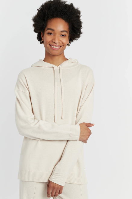 Person wearing a cream-colored hoodie on a white background