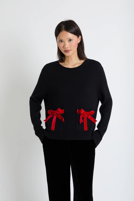 Woman wearing a black sweater with red bows on a white background
