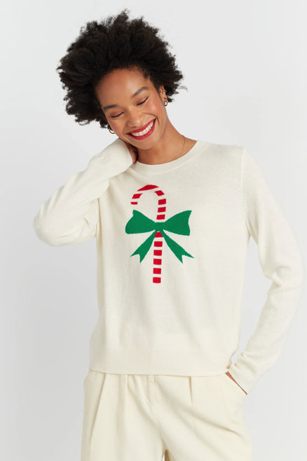 Person wearing a cream sweatshirt with a candy cane and bow design on a white background