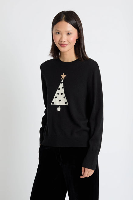 Woman wearing a black sweater with a white Christmas tree design on a white background