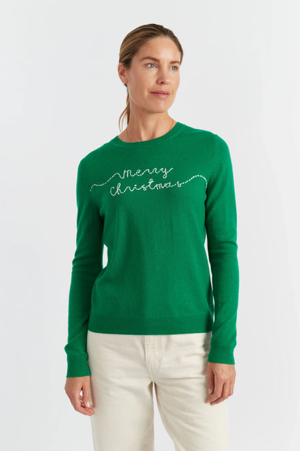 Woman wearing a green 'Merry Christmas' sweater on a white background