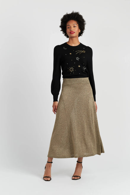 Woman wearing a black sweater with star patterns and a beige skirt on a white background