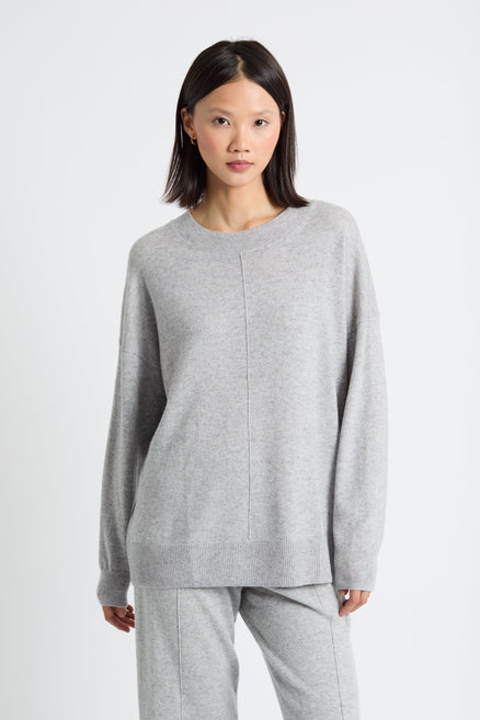 Woman wearing a grey sweater and pants on a white background