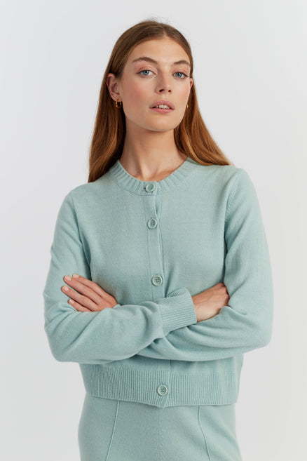 Woman wearing a light blue cardigan against a white background