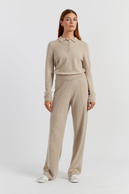 Woman wearing a beige long-sleeve polo shirt and matching pants on a white background