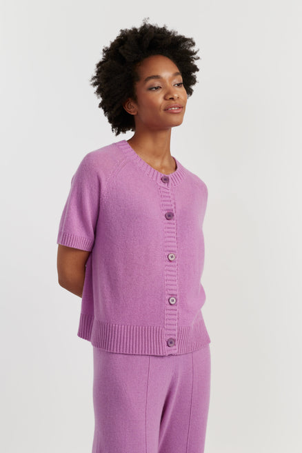 Woman wearing a purple outfit with a matching cardigan and pants on a white background