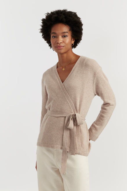 Woman wearing a beige wrap sweater on a white background