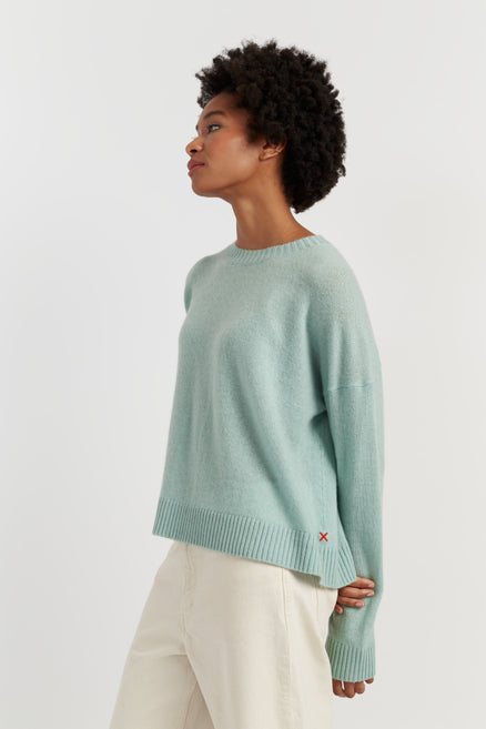 Person wearing a light green sweater on a white background