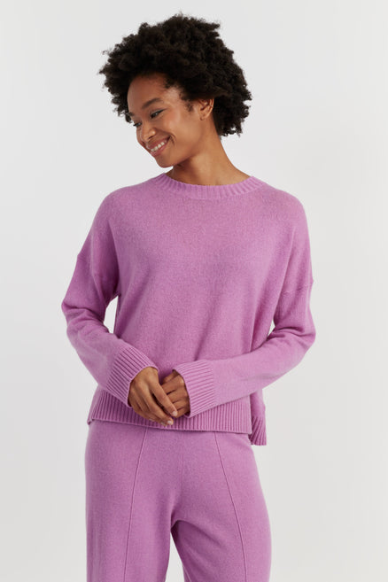 Woman wearing a lilac sweater and pants on a white background
