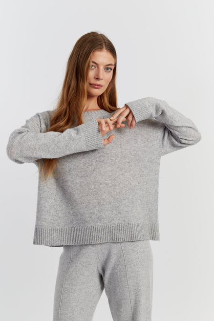 Woman wearing a grey sweater and pants on a white background