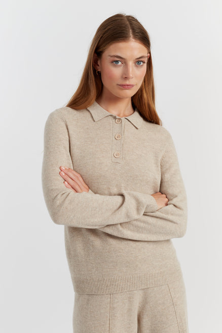 Woman wearing a beige sweater with a collar against a white background